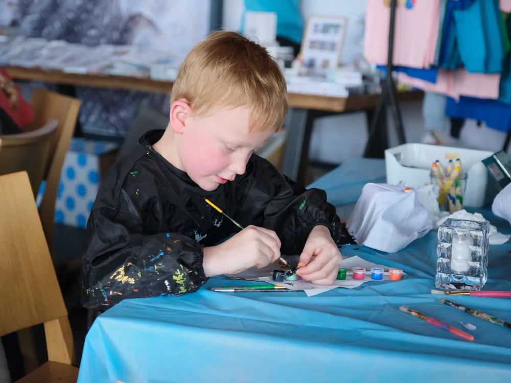 Een jongetje schildert aan de blauwe tafel bij het knutselcafé in Beachclub Lemmer