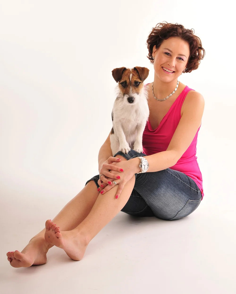 Carolien zit op de grond met haar hondje Joy op schoot en lacht